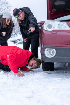 Friends assessing car trouble in the winter snow