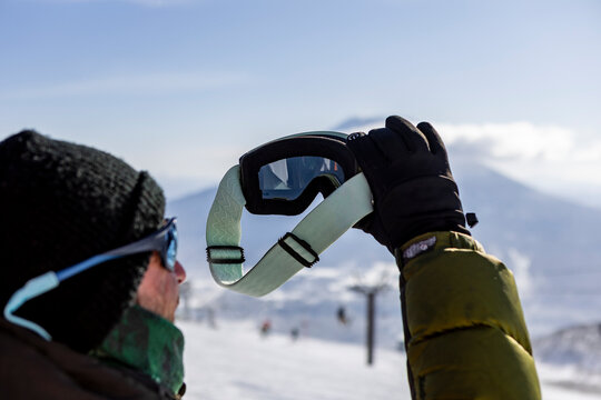 Skier holding goggles on snowy slope at mountain resort