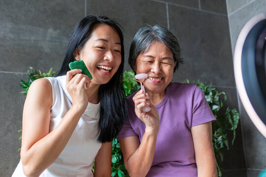 Two women using facial roller and gua sha at home