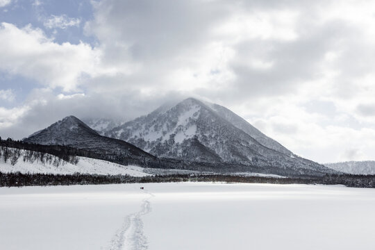 Splitboard track across snowy lake toward Japan mountain
