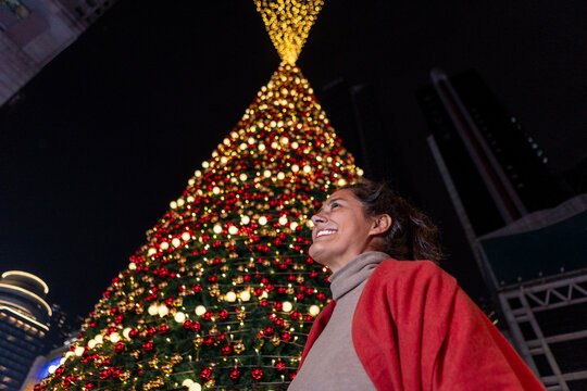 Woman smiling by giant Christmas tree at night in China
