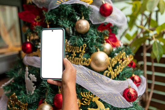 Smartphone mockup in hand with decorated Christmas tree