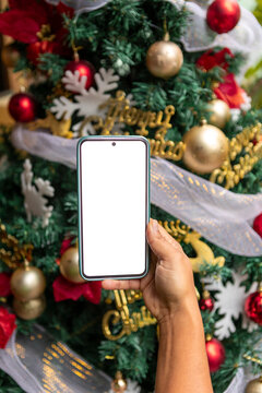 Smartphone mockup held in front of decorated Christmas tree
