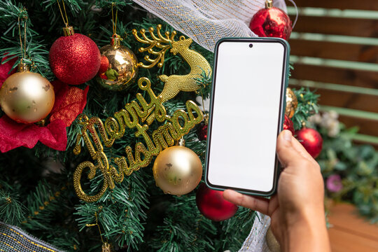 Smartphone mockup by Christmas tree with festive ornaments
