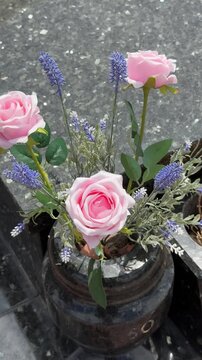 Artificial pink roses and lavender arrangement in cemetery vase