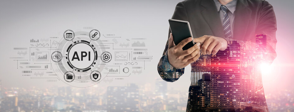 Professional Businessman Using Mobile Device with API Graphics Overlay against City Skyline for Digital Innovation and Connectivity Concept. Entropy.