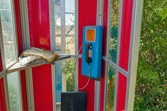Rotting directories lay on the shelf of a vintage red phone booth
