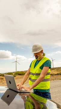 Wind turbine technician using laptop at renewable site