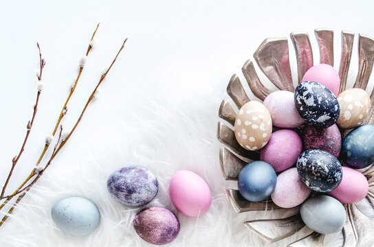 Pastel Easter eggs in a metal bowl on white background