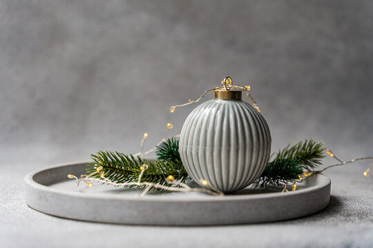 Grey Christmas bauble with fir and fairy light on tray