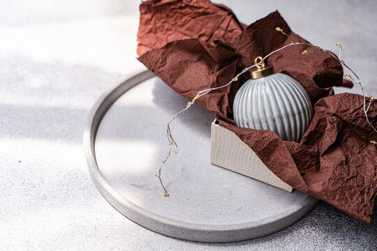 Grey Christmas bauble in box with brown tissue on tray