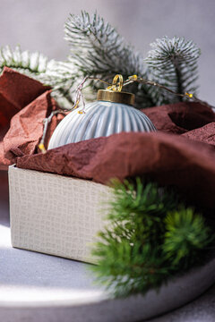 Grey Christmas bauble in gift box with pine and lights