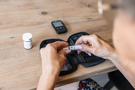 Person preparing glucose test kit and lancet at home