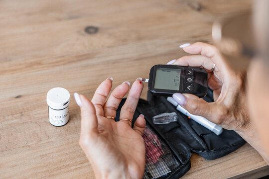 Woman checking blood sugar with glucometer at home