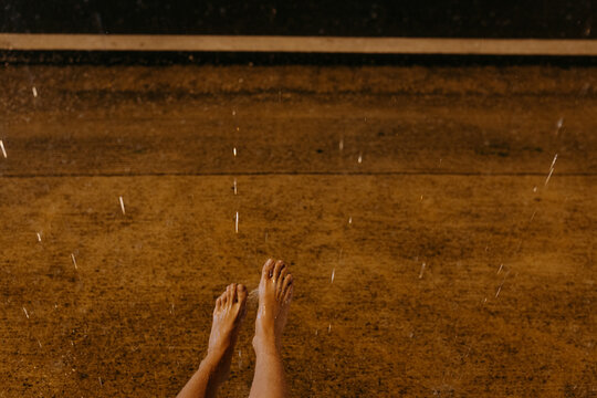 Bare feet in rain on wet pavement at night with splashes