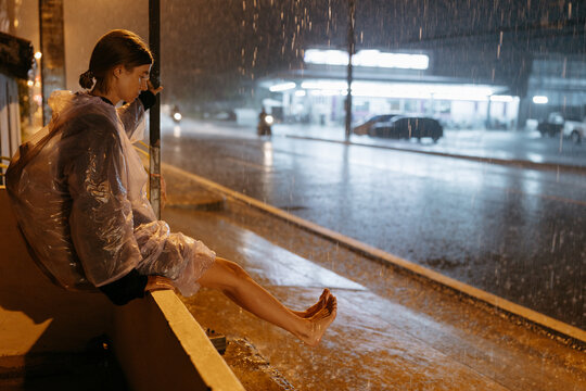 Woman waiting in heavy rain at night on city street