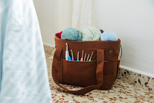 Crochet bag with yarn balls and hooks on terrazzo floor