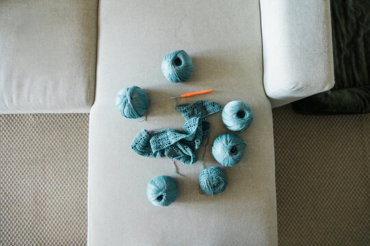 Crochet project with blue yarn balls and hook on sofa