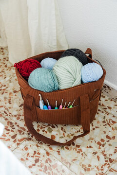 Knitting bag with colorful yarn and crochet hooks indoors