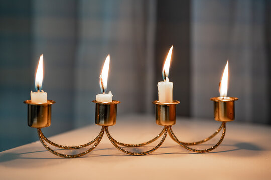 Candelabro dorado con cuatro velas encendidas sobre mesa, iluminaci&oacute;n c&aacute;lida y ambiente elegante