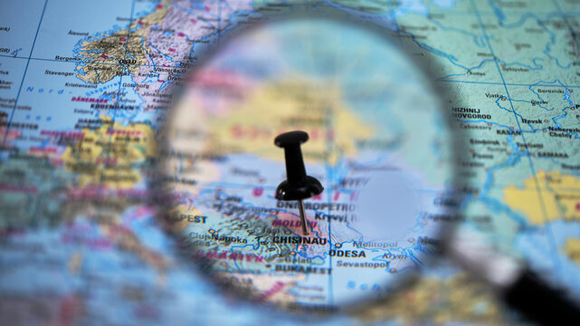 Exploring a map with a magnifying glass and a pin in Chisinau