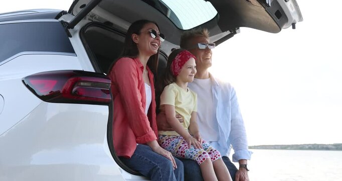 Happy family in trunk of car near sea