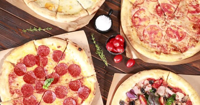 Different yummy pizzas and ingredients on wooden table, flat lay