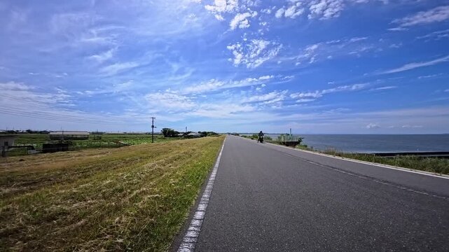 Asphalt cycling path running alongside a scenic riverbank under blue sky