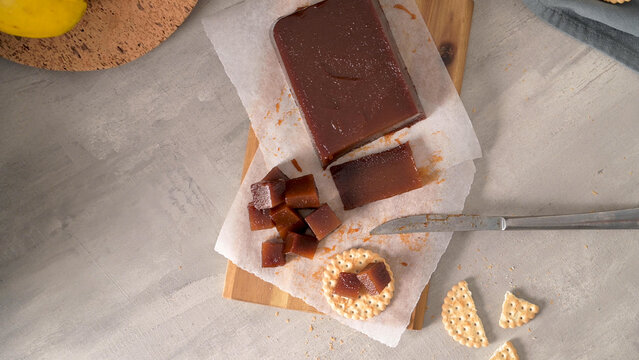 Quince paste block and cubes on parchment paper with crackers