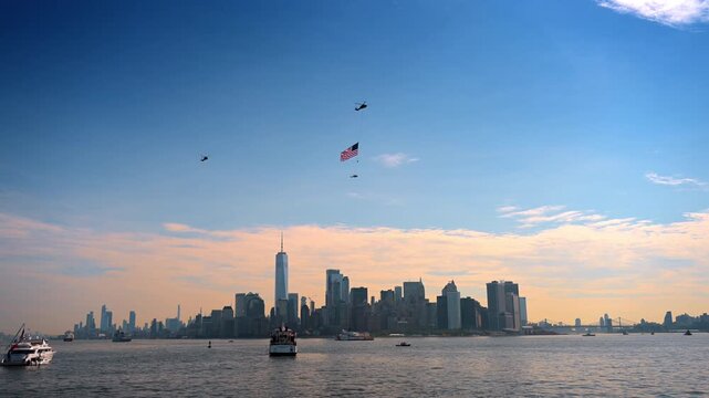 Formation of helicopters with an American flag over Manhattan. Aircraft fly across the golden evening sky above the cityscape during Independence Day.