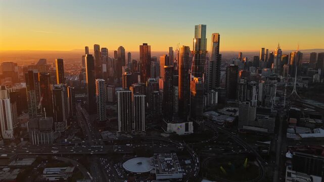 Aerial drone video moving left near Southbank at sunset, showing high-rise towers in the foreground and the Melbourne CBD skyline glowing in the background