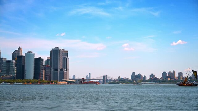 Brooklyn Bridge between Lower Manhattan and Brooklyn. A distant suspension span crosses blue water below a broad sky on Independence Day.