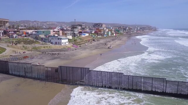Aerial view of the international border wall between the united states and mexico on the pacific ocean beach.