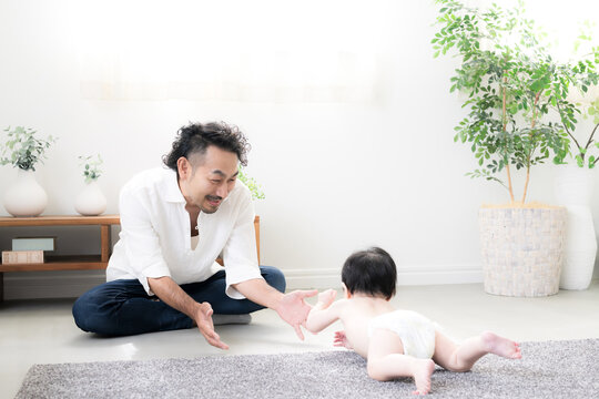 A father watching over his baby as it crawls&mdash;an image of a hands-on dad on paternity leave with his baby, depicting parenting, child-rearing, growth, and parent-child bonding