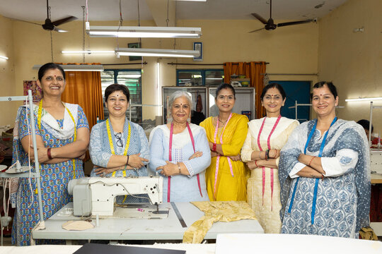 Confident Indian skilled woman worker standing inside a textile export house with arms crossed and looking directly at the camera