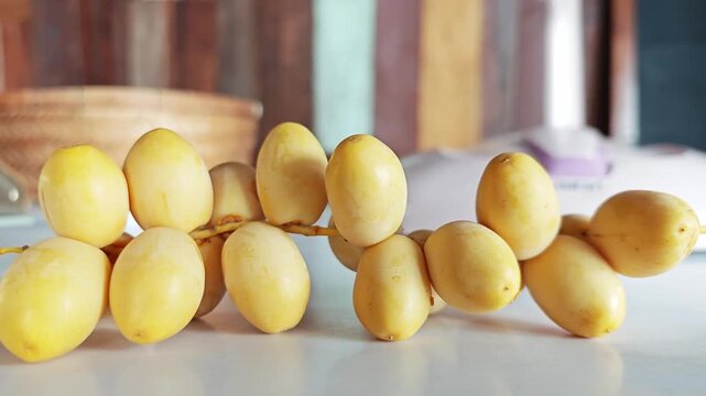 Fresh Yellow Dates Branch on White Table Closeup.