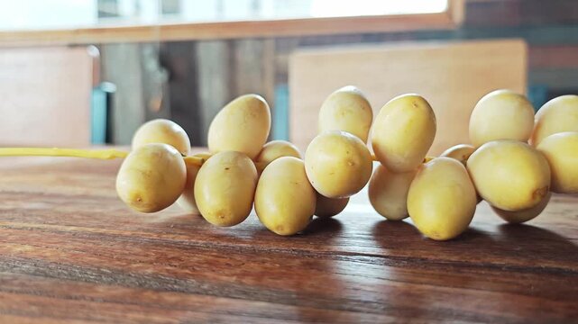 Fresh Yellow Date Palm Branch on Warm Wooden Table Closeup.