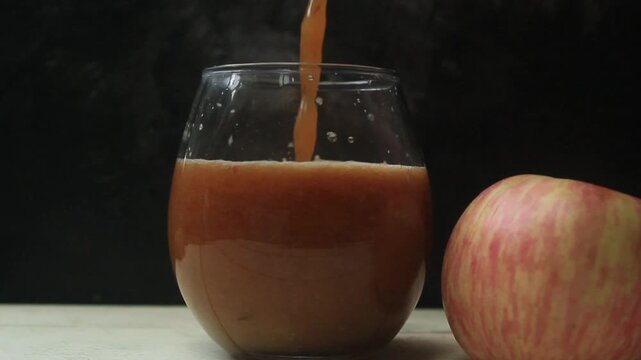 flat lay of pouring apple juice into a glass on a table