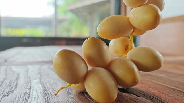 Fresh Yellow Date Palm Cluster Hanging Over Wooden Table.