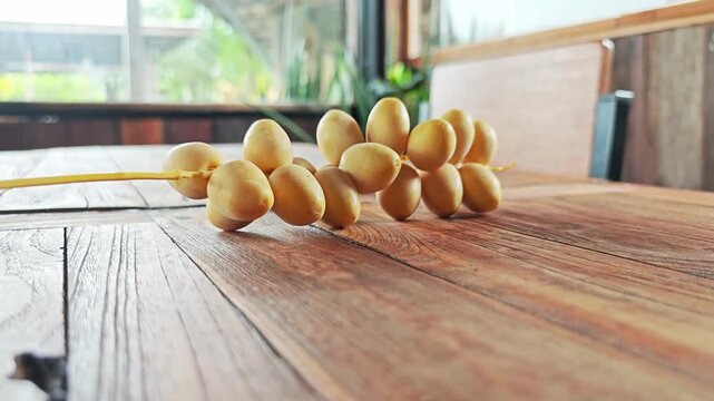 Fresh Yellow Date Palm Branch on Warm Wooden Table.