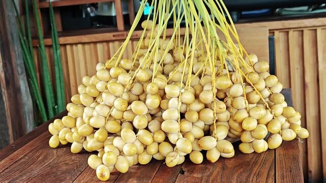 Fresh Yellow Date Palm Bunch Hanging Vertically Over Wooden Table.