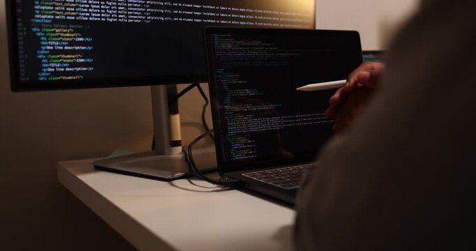 Software developer writing, reviewing and debugging source code across multiple screens using tablet and computer in modern workspace for software engineering, programming and application development.