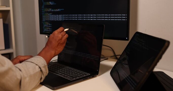 Software developer writing, reviewing and debugging source code across multiple screens using tablet and computer in modern workspace for software engineering, programming and application development.