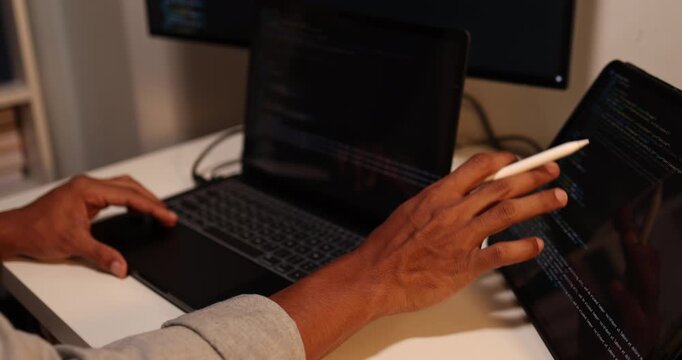 Software developer writing, reviewing and debugging source code across multiple screens using tablet and computer in modern workspace for software engineering, programming and application development.