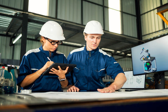 Two engineers discussing blueprints in a modern industrial facility.