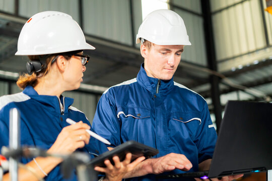 Engineers using laptop in factory Industrial team reviewing technical project plans.
