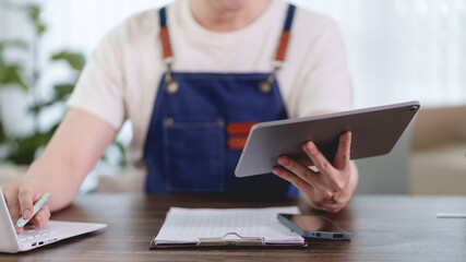 Asian woman online merchant holding digital tablet while managing laptop business in modern workspace with copy space © Audtakorn