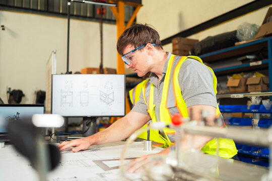Engineer reviewing blueprints in workshop Industrial designer working on technical plans.