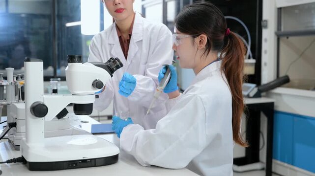 Young scientists conducting research investigations in a medical laboratory, a researcher in the foreground is using a microscope in laboratory for medicine.