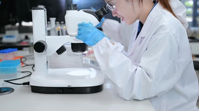 Young scientists conducting research investigations in a medical laboratory, a researcher in the foreground is using a microscope in laboratory for medicine.